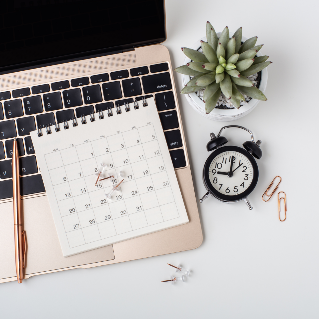 laptop, clock, calendar, plant on desk planning