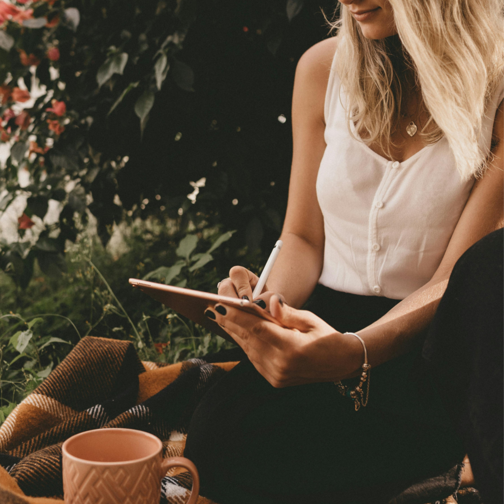 woman writing in nature on digital tablet