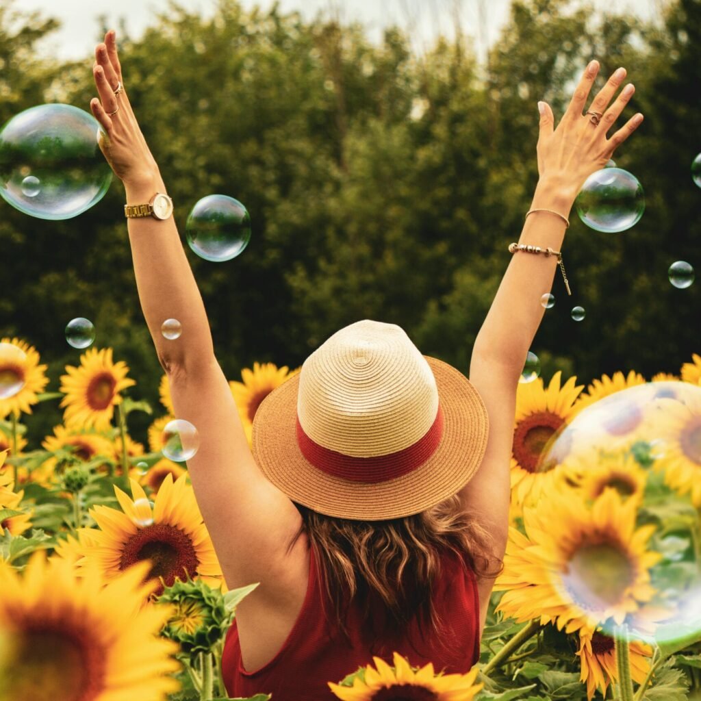A joyful woman in a sunflower field with bubbles, expressing happiness on a summer day.