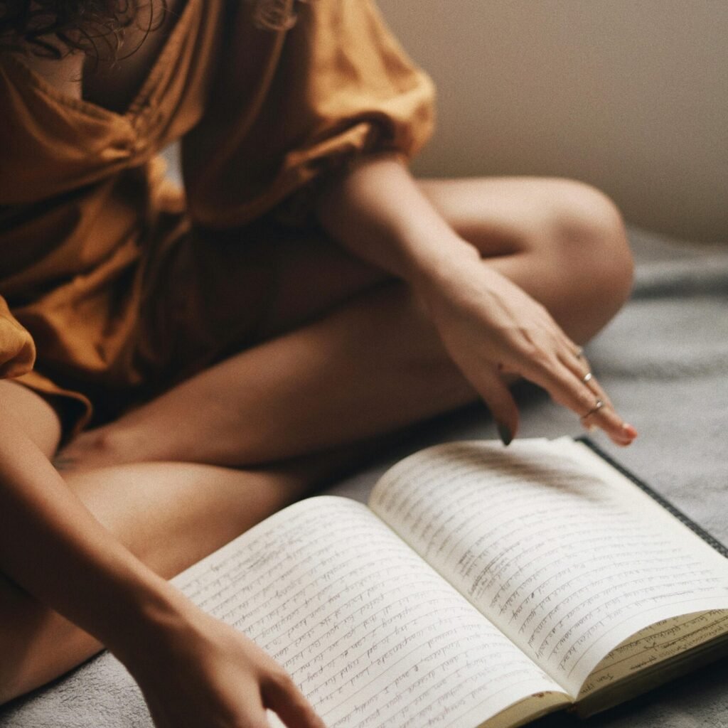 A woman sits cozily reading a book near a window, embracing leisure time.
