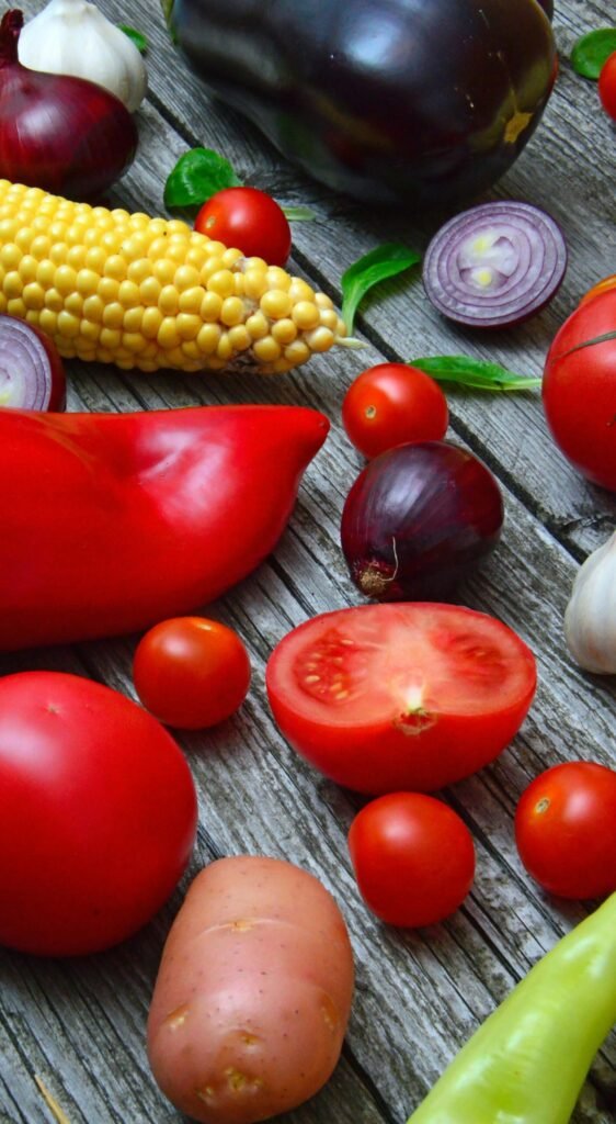 A vibrant assortment of fresh vegetables on a rustic wooden table, ready for cooking.