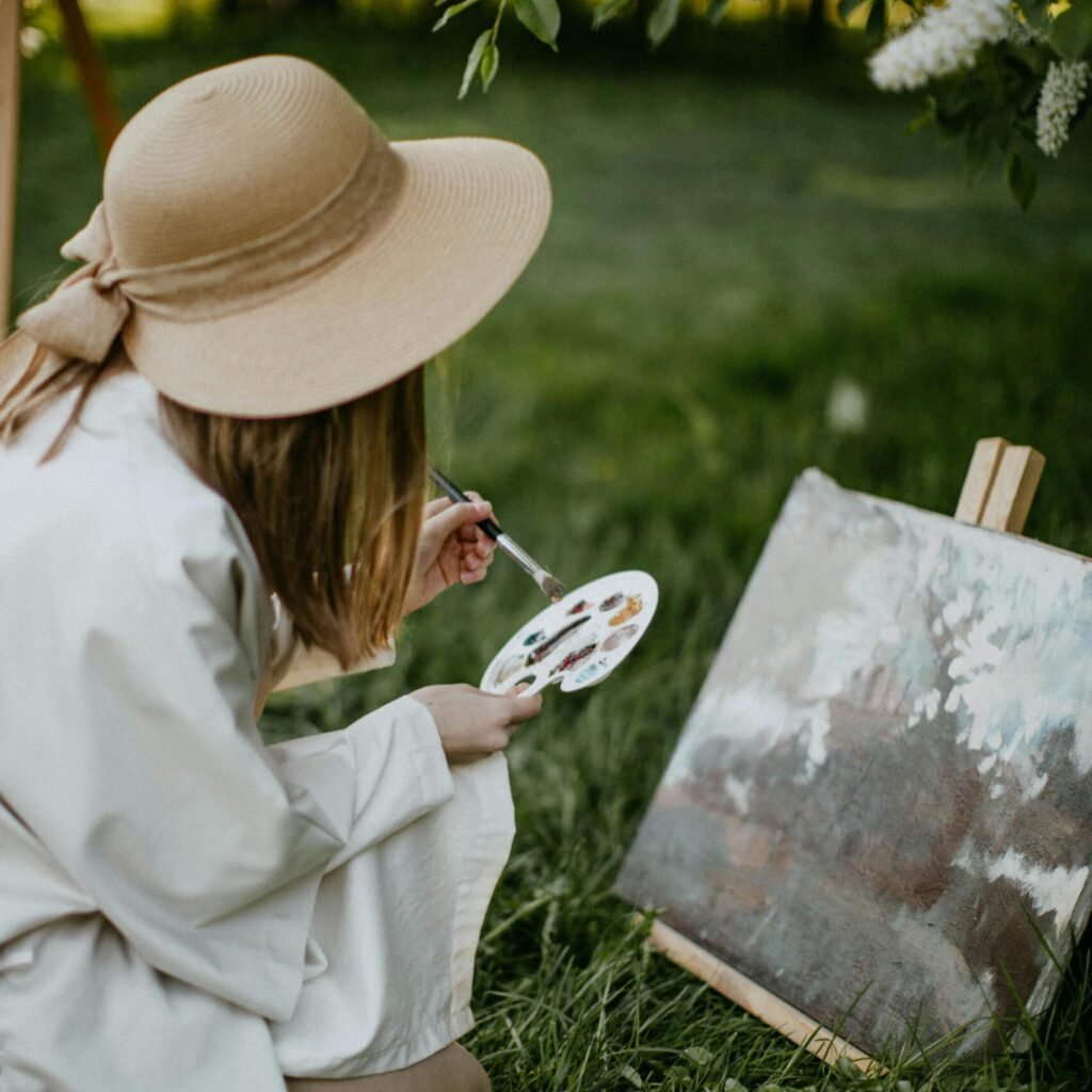 Young woman painting in a lush garden, capturing nature's beauty in spring.
