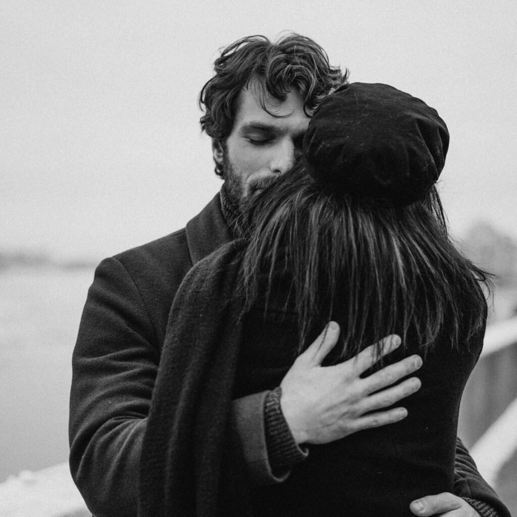 A couple shares an intimate embrace in a black and white photo, conveying love and togetherness.