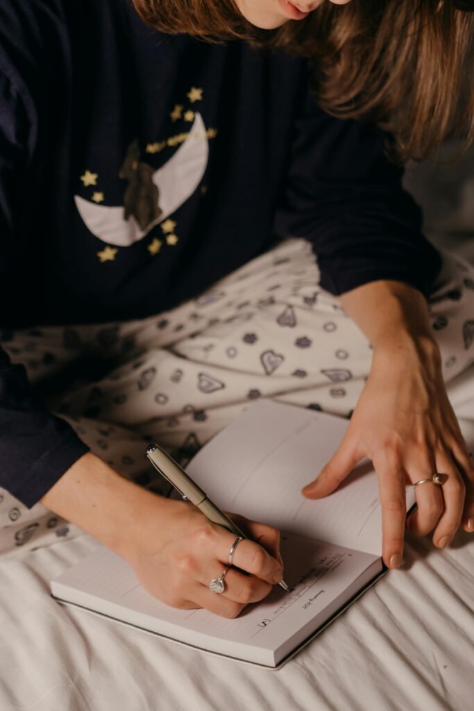 A woman in cozy pajamas writing in a notebook, indoors, night time routine, journaling, sunday reset