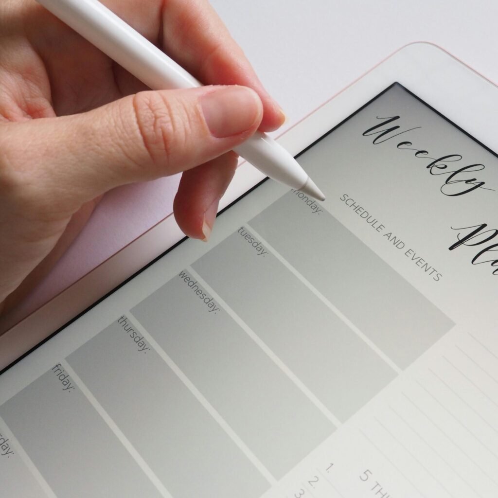 A stylus writing in a digital weekly planner on a tablet screen, ideal for organization.