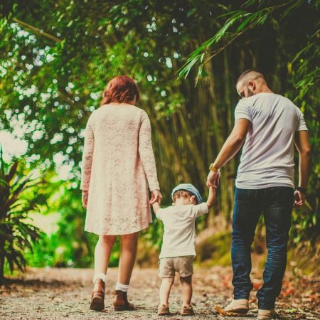 family walk outside A family enjoys a leisurely walk in a green park, embodying joy and togetherness.